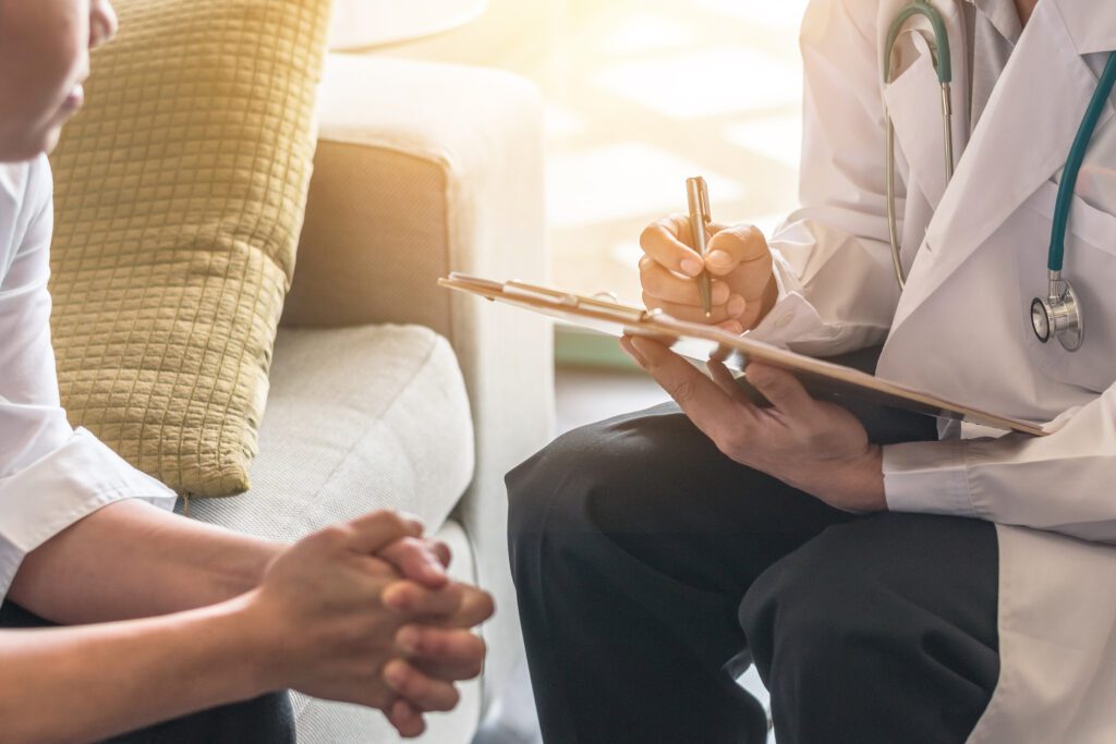 Image of a doctor's hands holding a clipboard talking to their patient for behavioral health evaluation